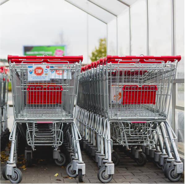 Two rows of red and silver shopping carts pushed together in a supermarket. 