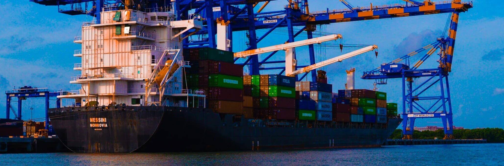 A commercial shipping port in India against a dark blue sky.