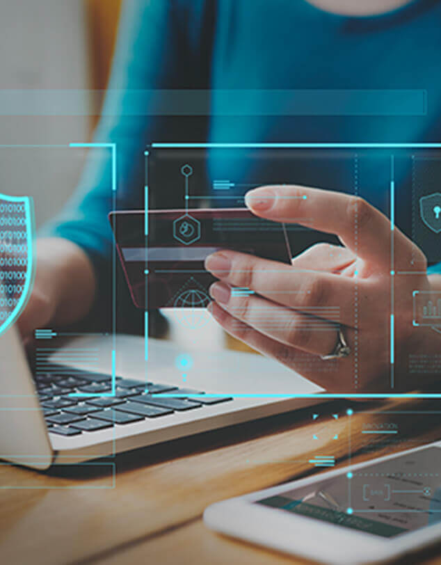 A woman's hands holding a credit card in front of a laptop and cell phone, with security and connectivity icons superimposed on them.