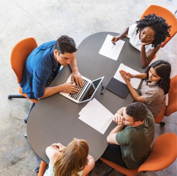 Overhead view of a group of students seated at a wooden table working together. 