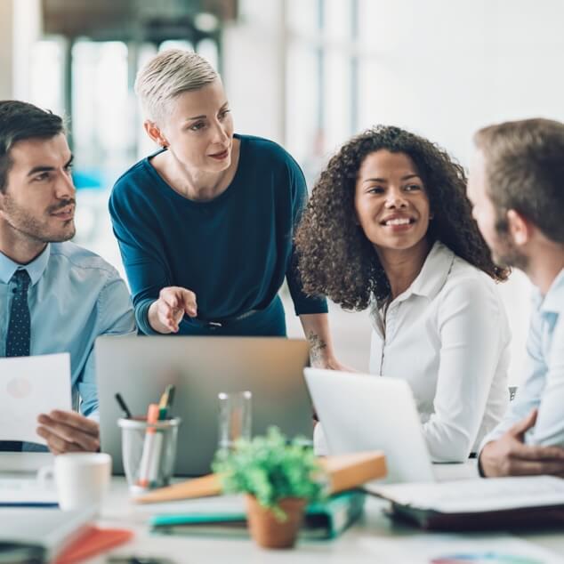 Four businesspeople collaborating on work over a laptop. 