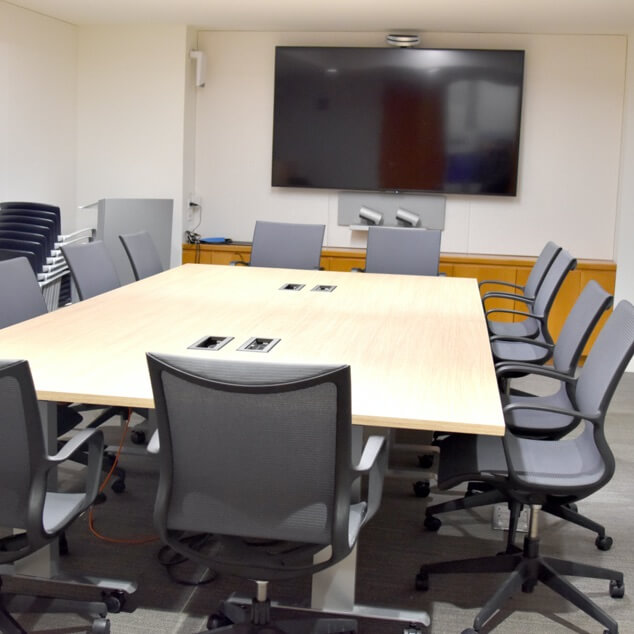 An airy meeting room with a table, chairs, and AV equipment. 