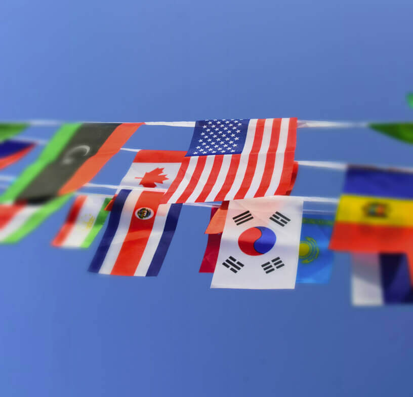 A group of international flags, including a U.S. flag, hanging from string banners. 