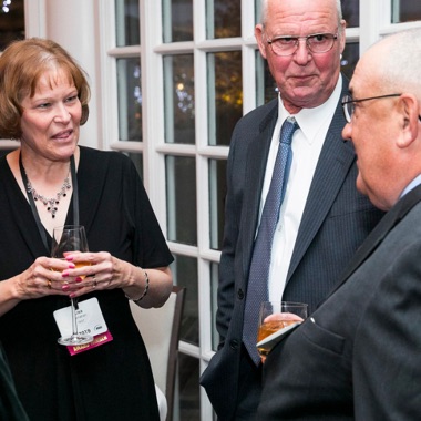 Three businesspeople talking and smiling at ANSI Awards reception. 