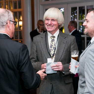 Three businessmen talking and smiling at ANSI Awards reception. 