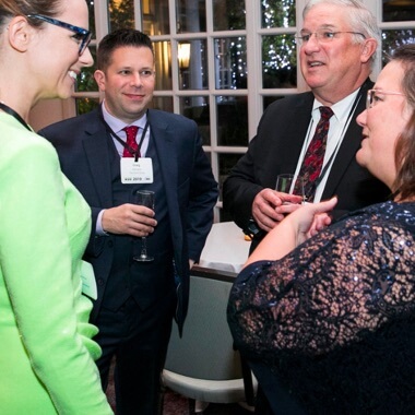 A group of businesspeople talking and smiling at ANSI Awards reception. 