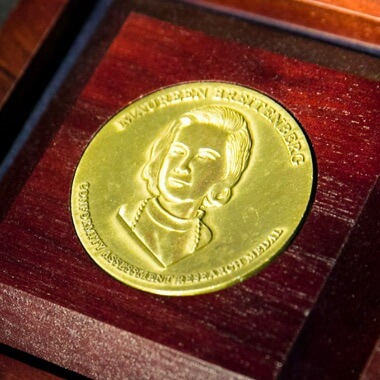 Closeup of golden ANSI leadership and service medal in wooden box.