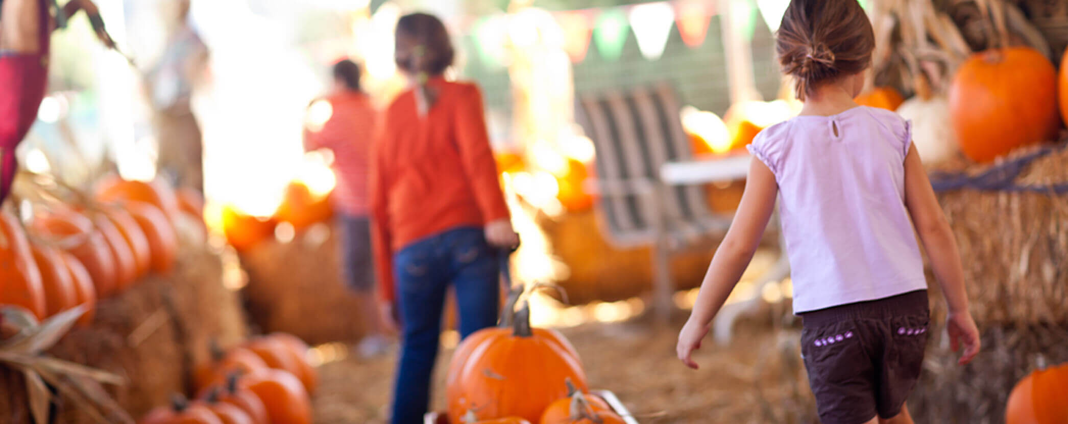 Kids carrying pumpkins at a fall festival.